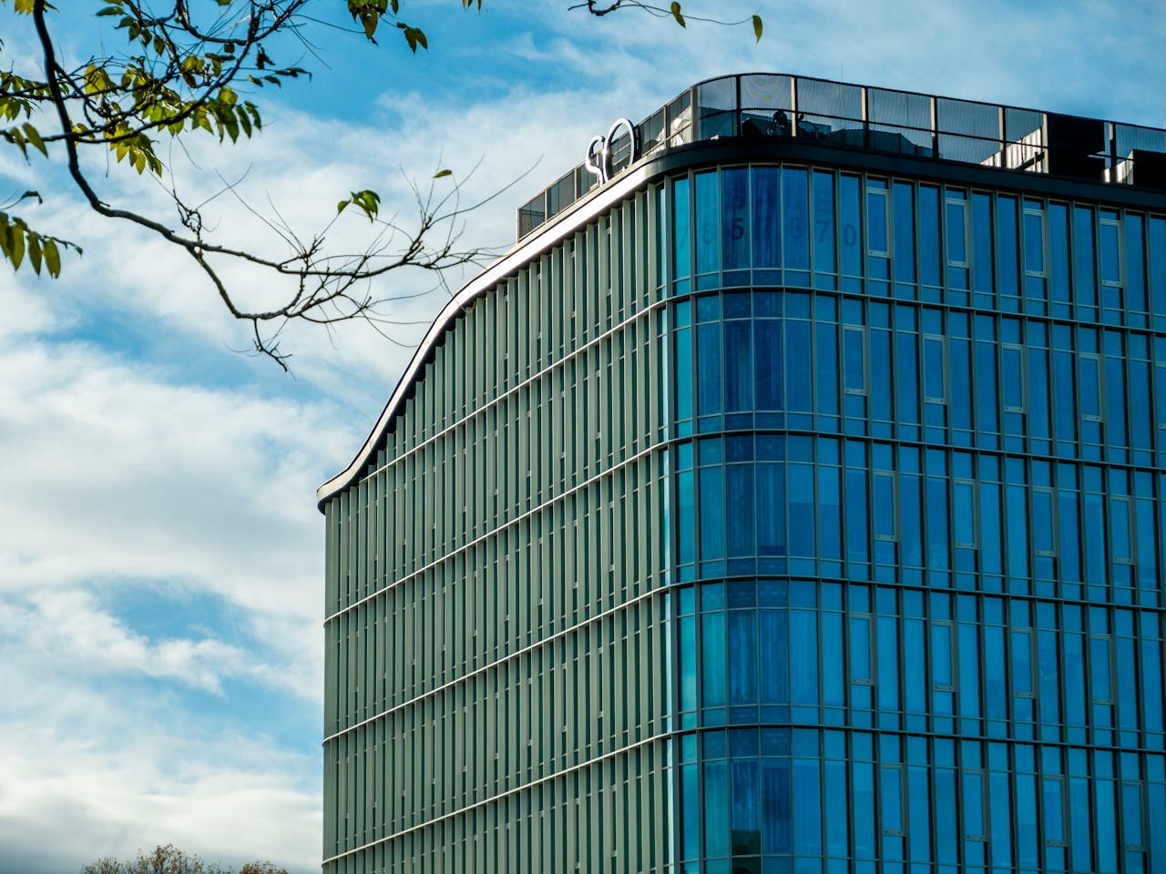 our-story A sleek, modern office building featuring curved glass and metal architecture under a clear blue sky.