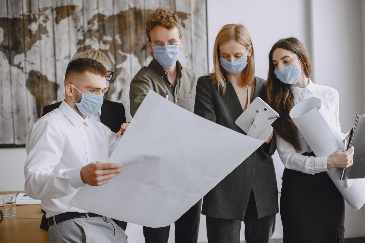 services-01 Office team discussing plans while wearing face masks for safety.